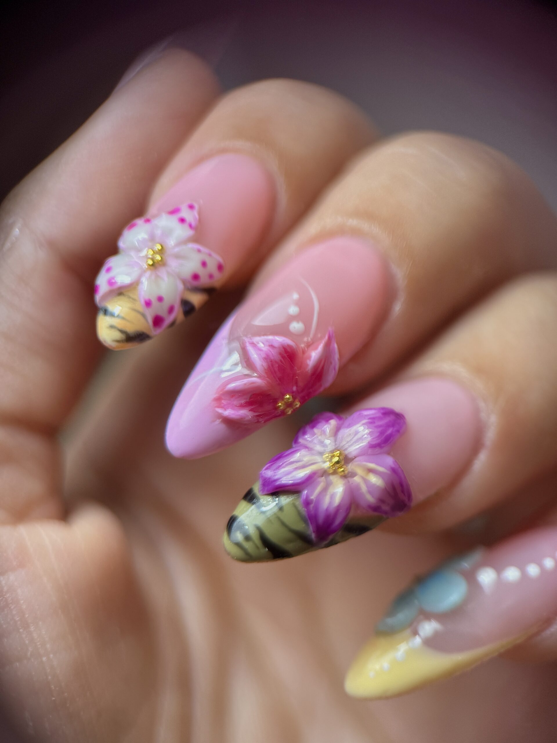 Nail art floral rose et violet avec fleurs en relief et touches dorées