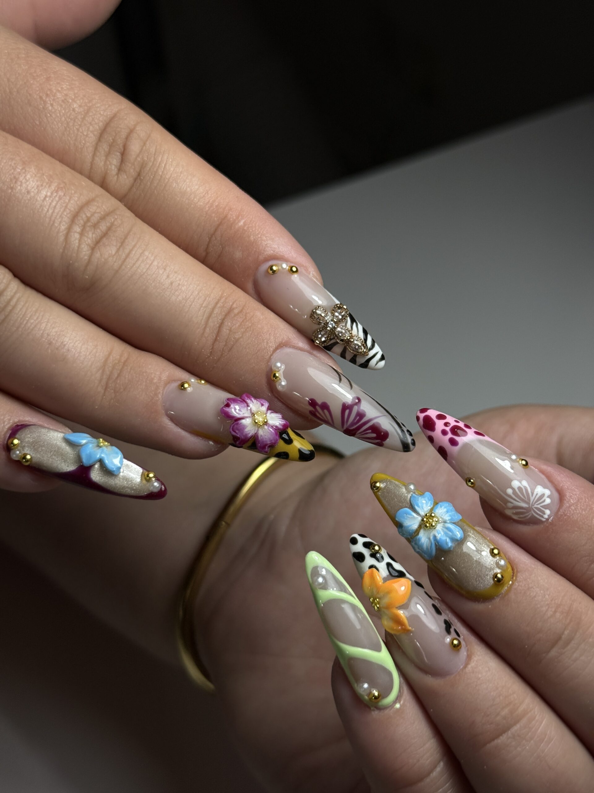 Ongles longs décorés de fleurs en relief, motifs colorés et détails dorés